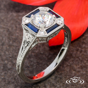 Platinum antique inspired design with custom cut bagguette sapphires and (4) 1.6mm accent diamonds totaling .06ctw. Wheat engraving on outside and piece filigree design on sides. Center can be set with the diamond of your choice ~.75-0.90ct. 