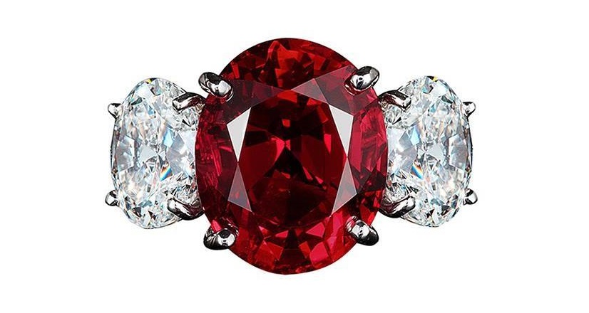  A ring centered upon a fiery 8 carat imperial red Thai ruby flanked by oval diamonds