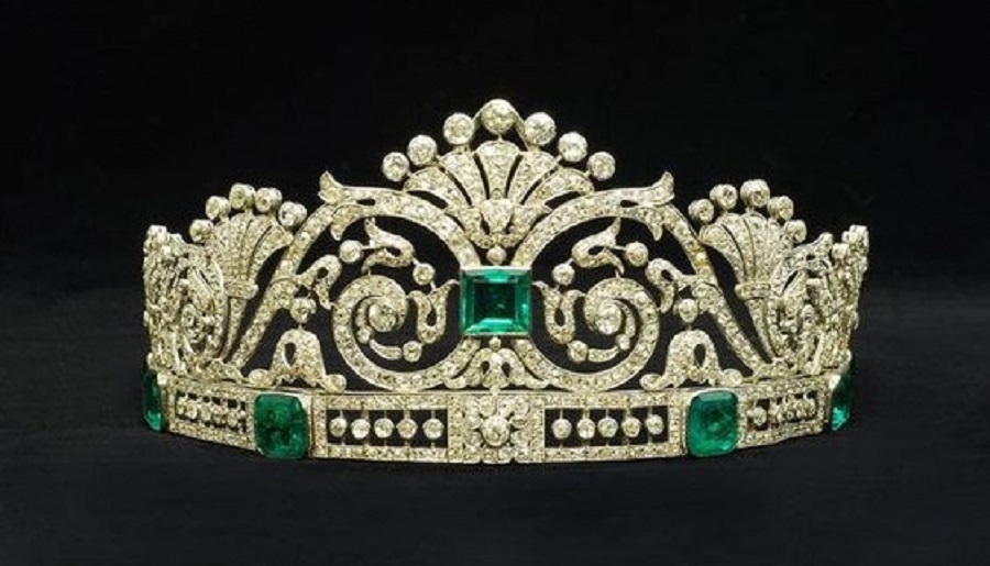 An emerald and diamond tiara in a fitted case by Marzo. The central square-cut emerald set amidst a tapering openwork panelof scrolling foliate motifs, mounted atop a band set with six graduated cut-cornered step-cut emeralds interspersed with openwork panels with knife-edge set diamond collets, the piece set throughout with old and rose-cut diamond. Circa 1915. This tiara has been in the private ownership of a Spanish aristocratic family.